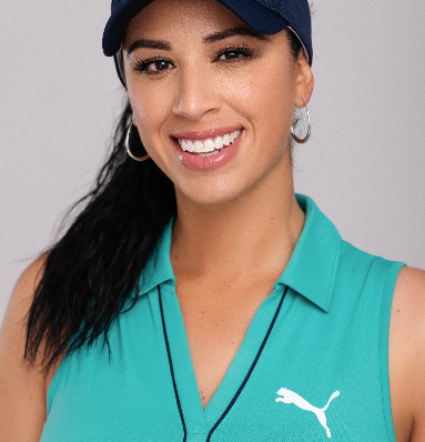 A woman wearing a blue puma shirt and a hat smiles for the camera