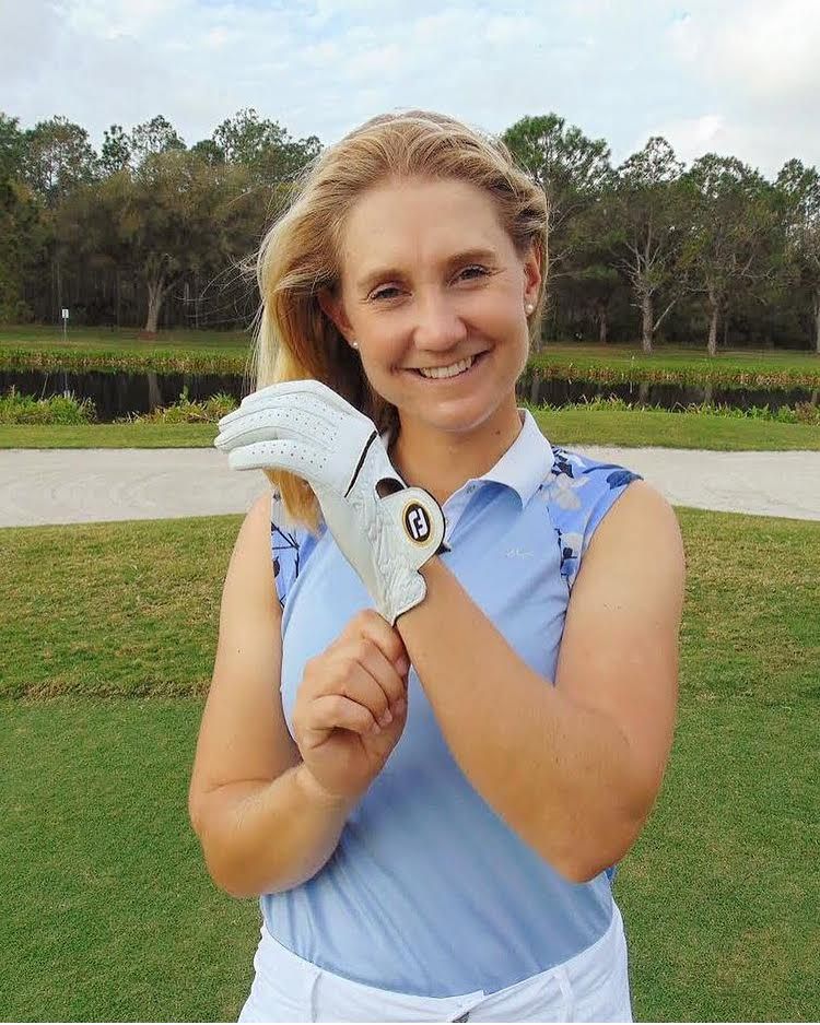 A woman is holding a golf glove with the letter g on it