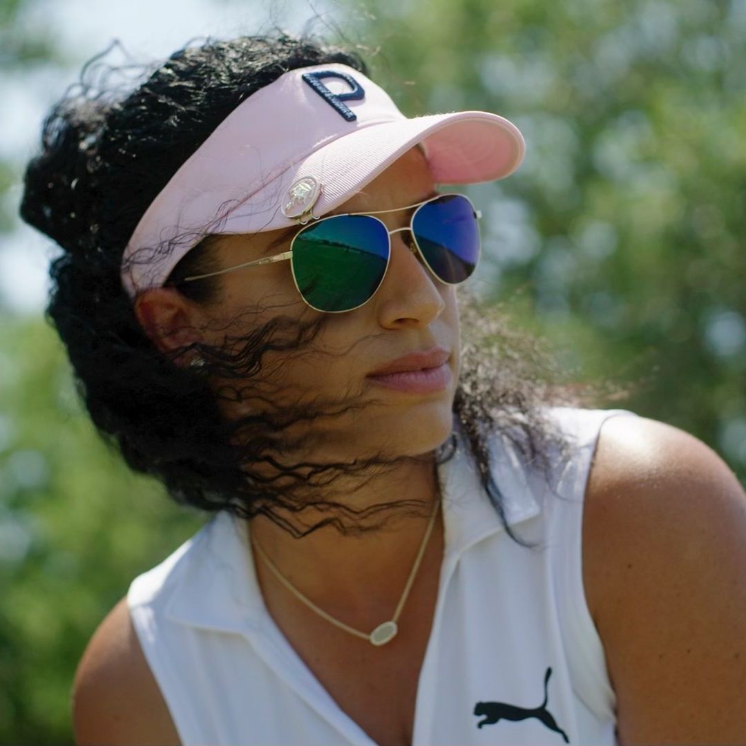 A woman wearing sunglasses and a pink hat with the letter p on it