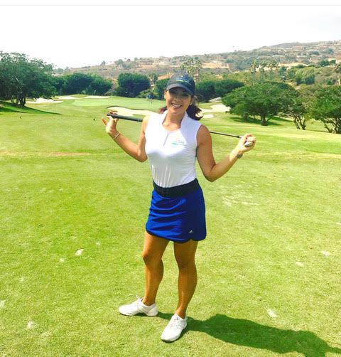 A woman is holding a golf club on a golf course