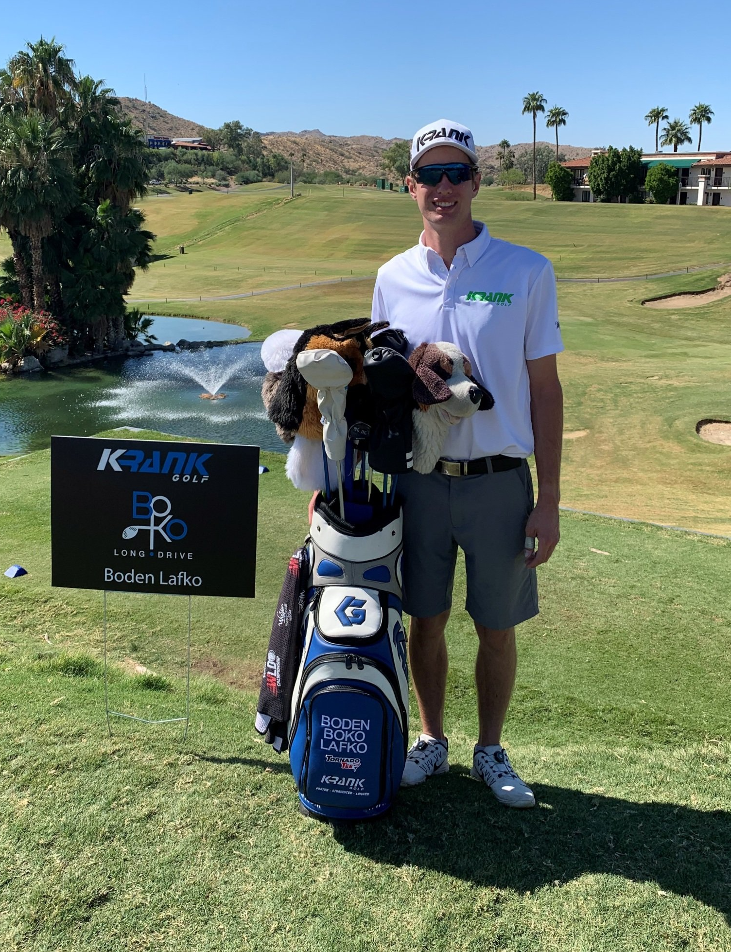 A man is standing next to a golf bag on a golf course.