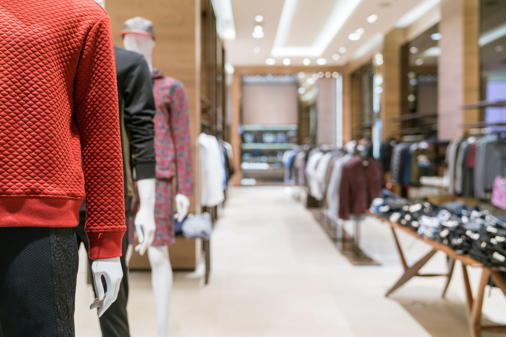 Inside a clothing store, mannequins display clothes, with racks of garments and merchandise on display.