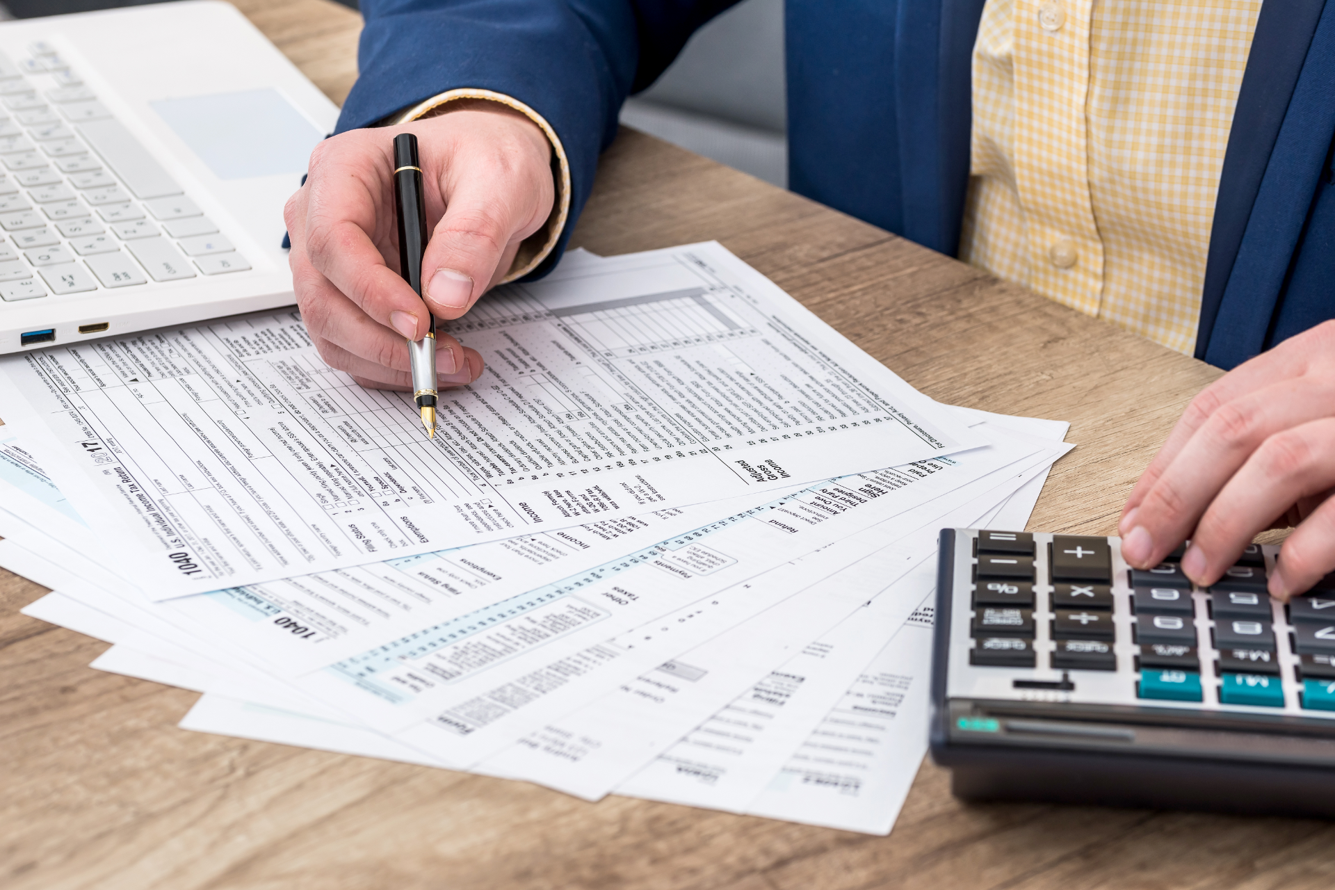 Person reviewing financial documents with a pen beside a calculator on a desk