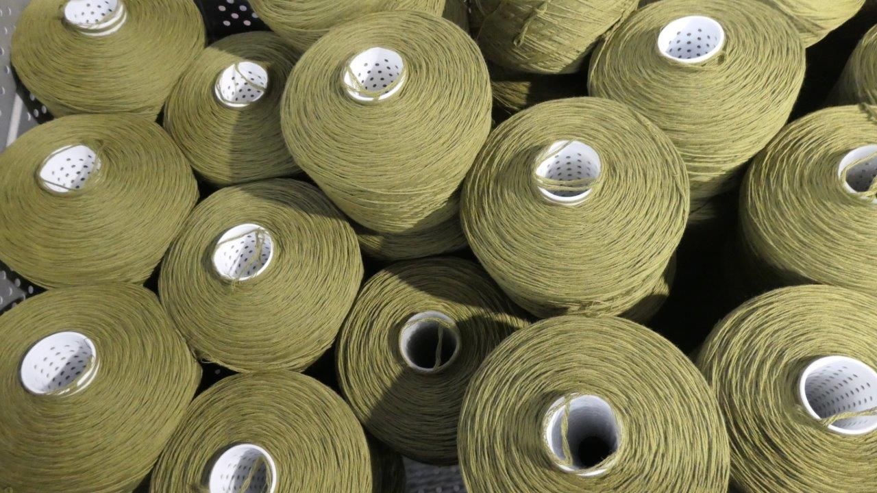 Una vista dall'alto di numerose bobine di filato verde oliva disposte insieme.