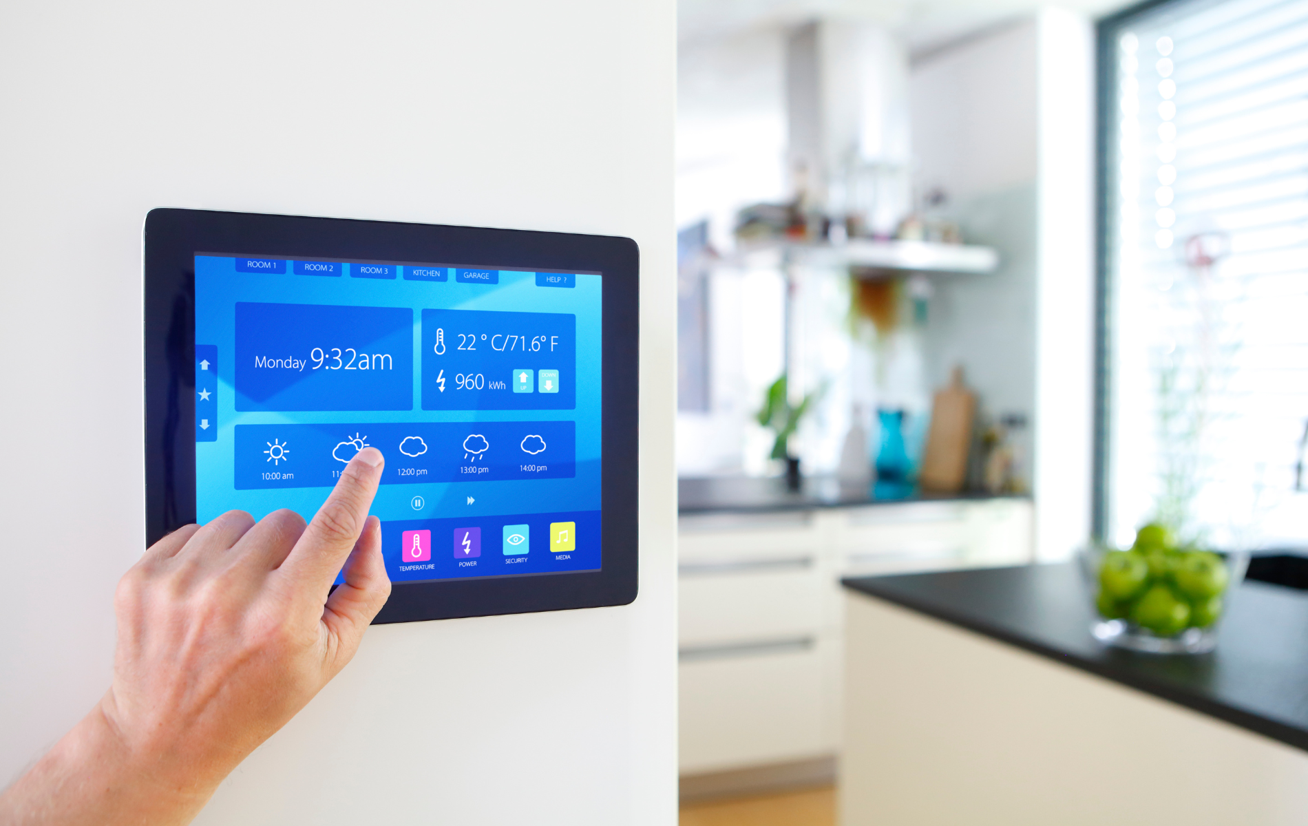 Person's finger touching a smart home control panel on a wall in a modern kitchen.