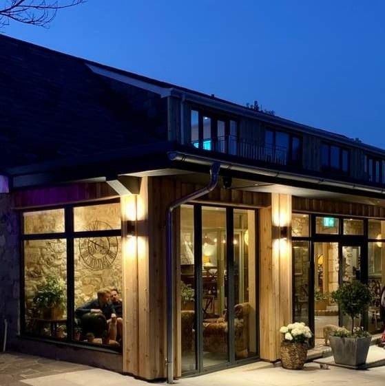 Building exterior at dusk, featuring wood paneling, large windows, and outdoor lighting.