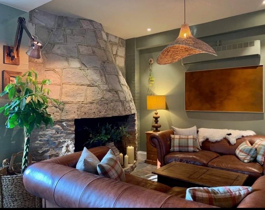 Cozy living room with a stone fireplace, leather sofas, and warm lighting.