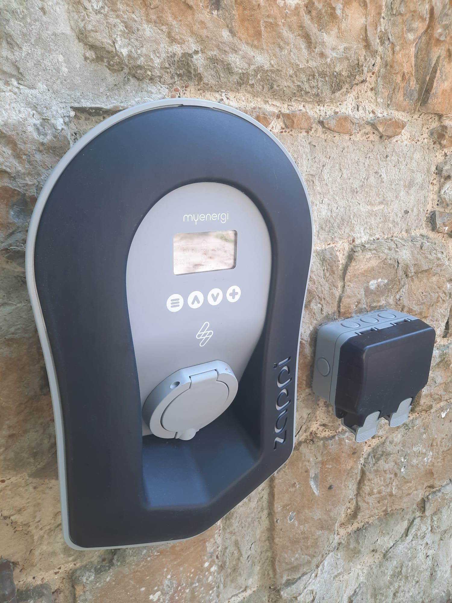 EV charging station mounted on a stone wall, gray and black colors.