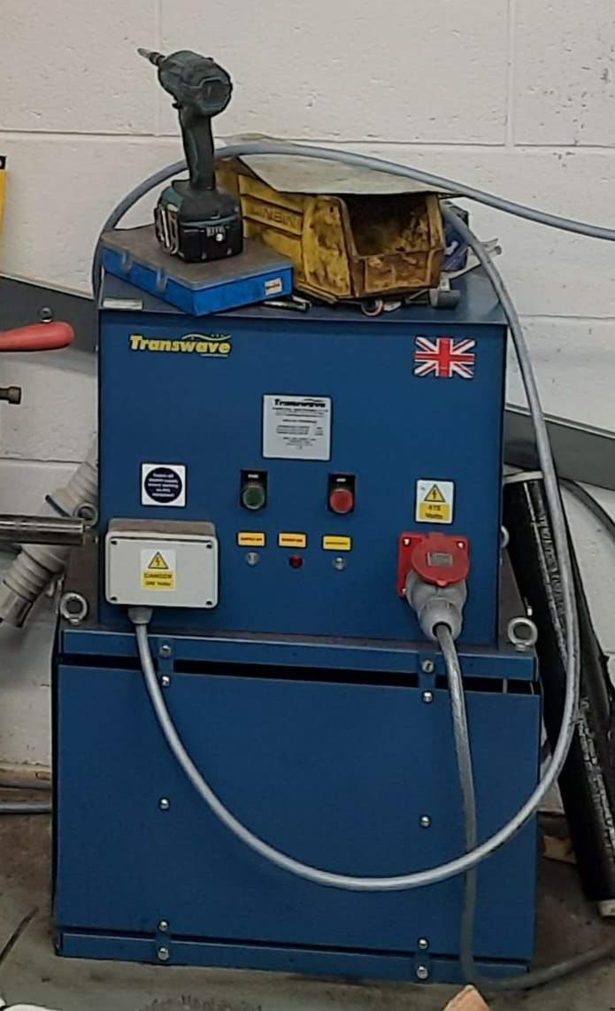 Blue electrical power unit with various controls, a red plug, and a Union Jack flag on the front, indoors.