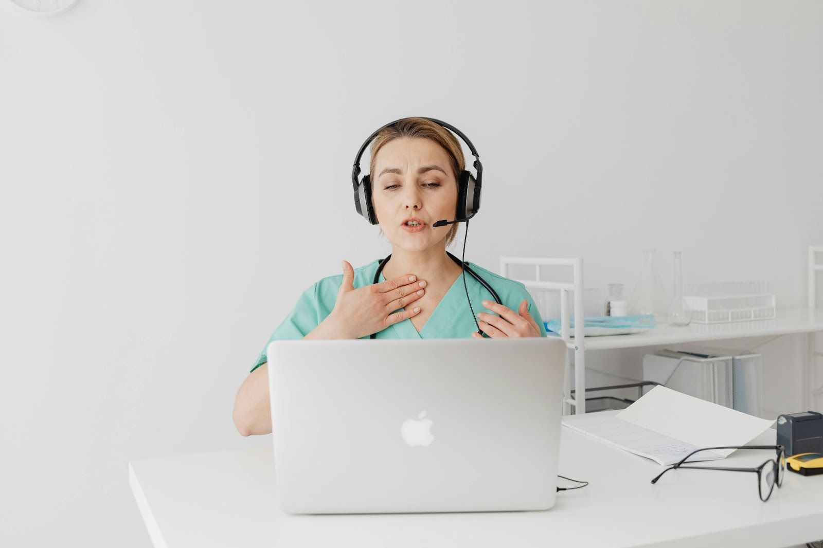 Woman wearing a headset speaking on a video call at a laptop in a bright office