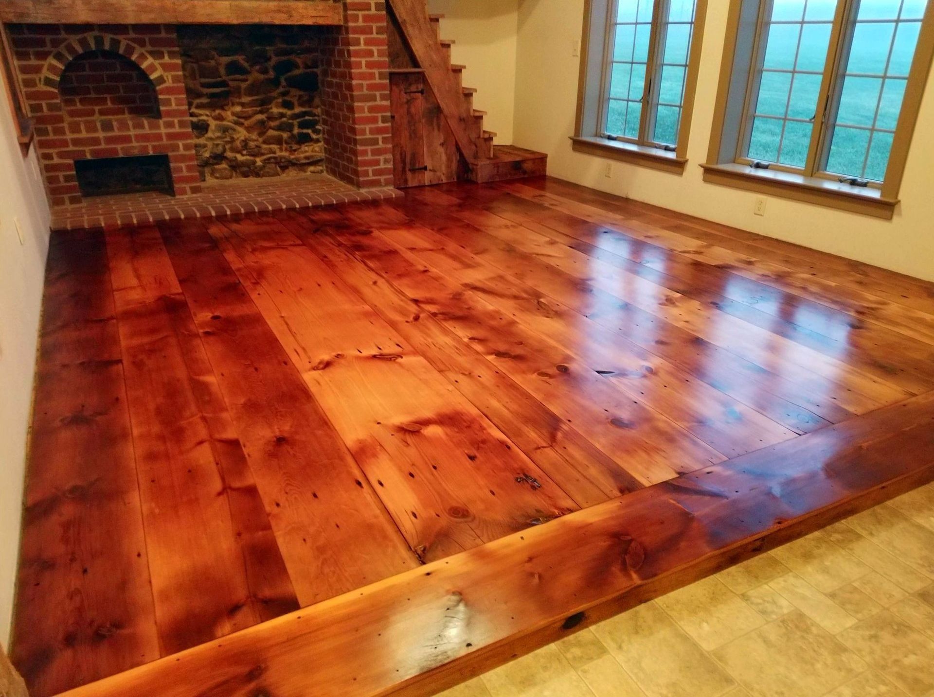 A living room with a wooden floor and a brick fireplace Galebach’s Floor Finishing