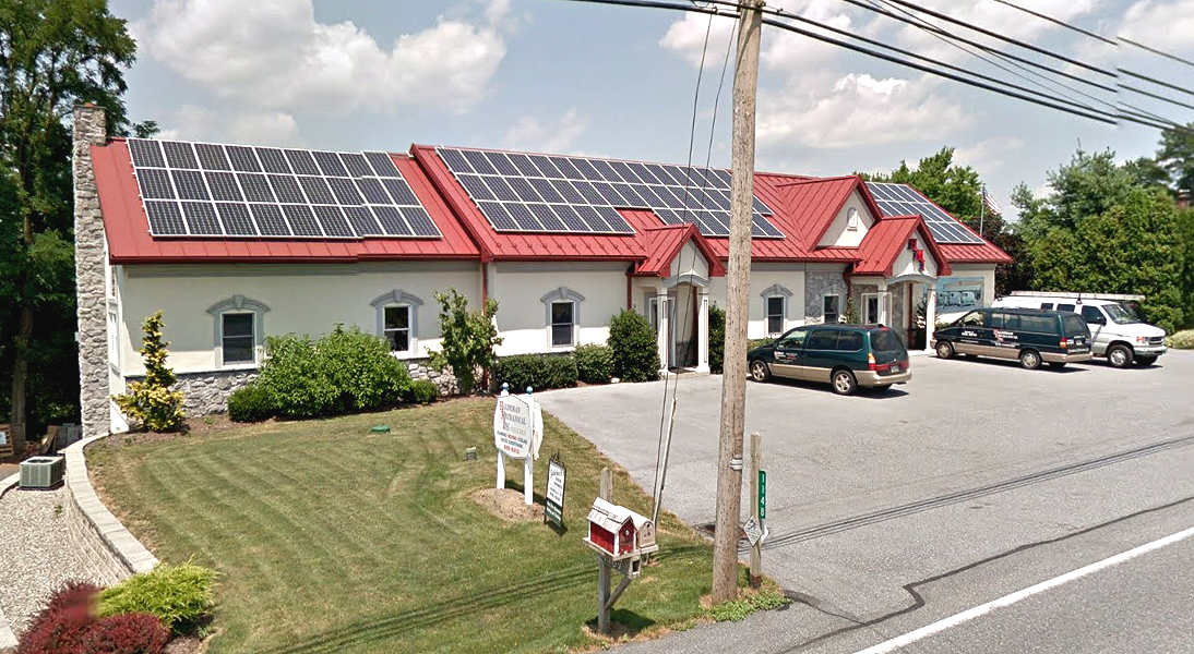A white building with a red roof and solar panels on it Galebach’s Floor Finishing