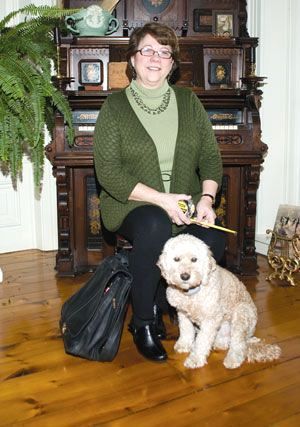 Karen from Galebach’s Floor Finishing is sitting on a chair next to a dog .