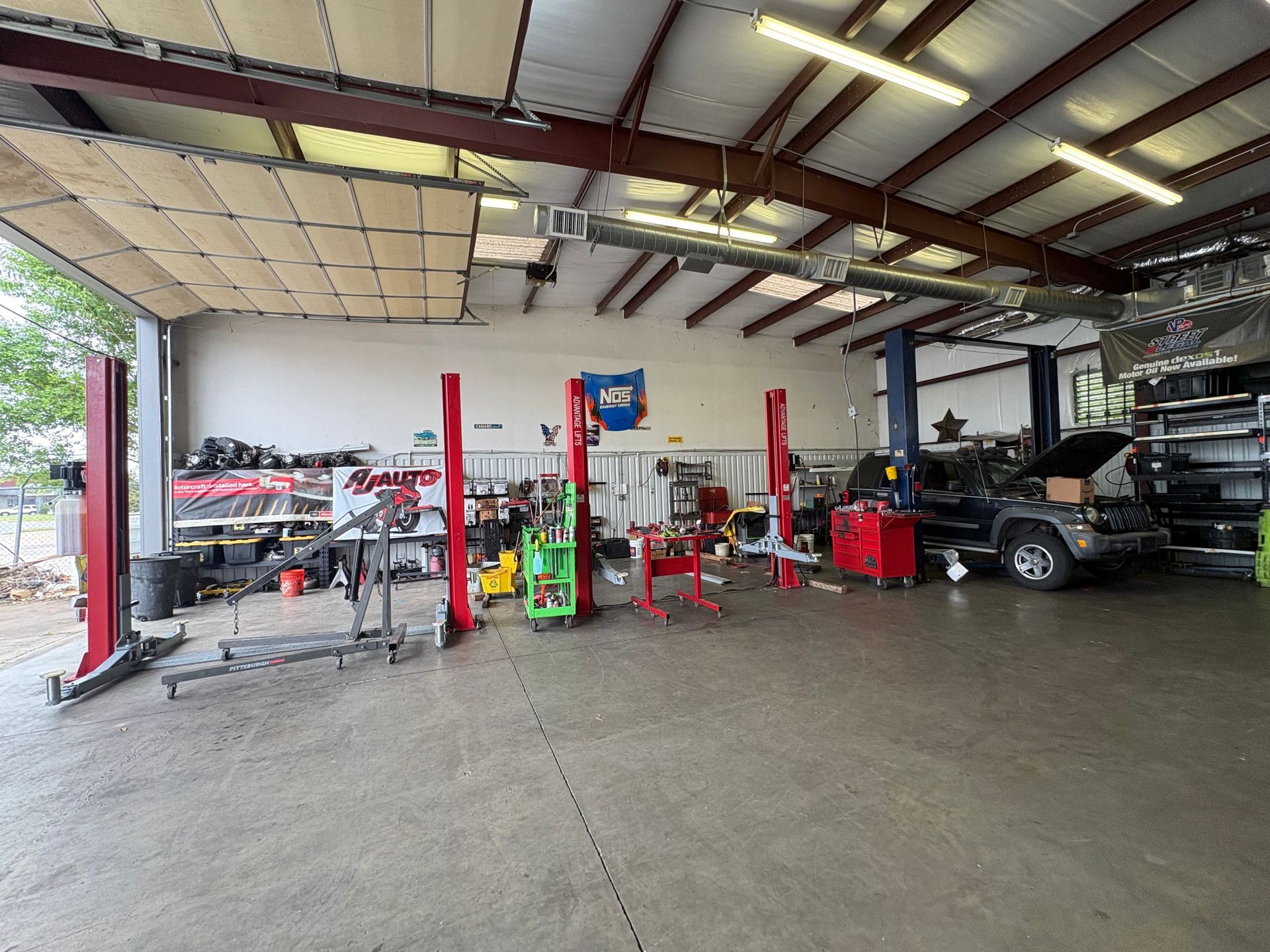 Auto repair shop interior with lifts, tools, and several vehicles parked inside