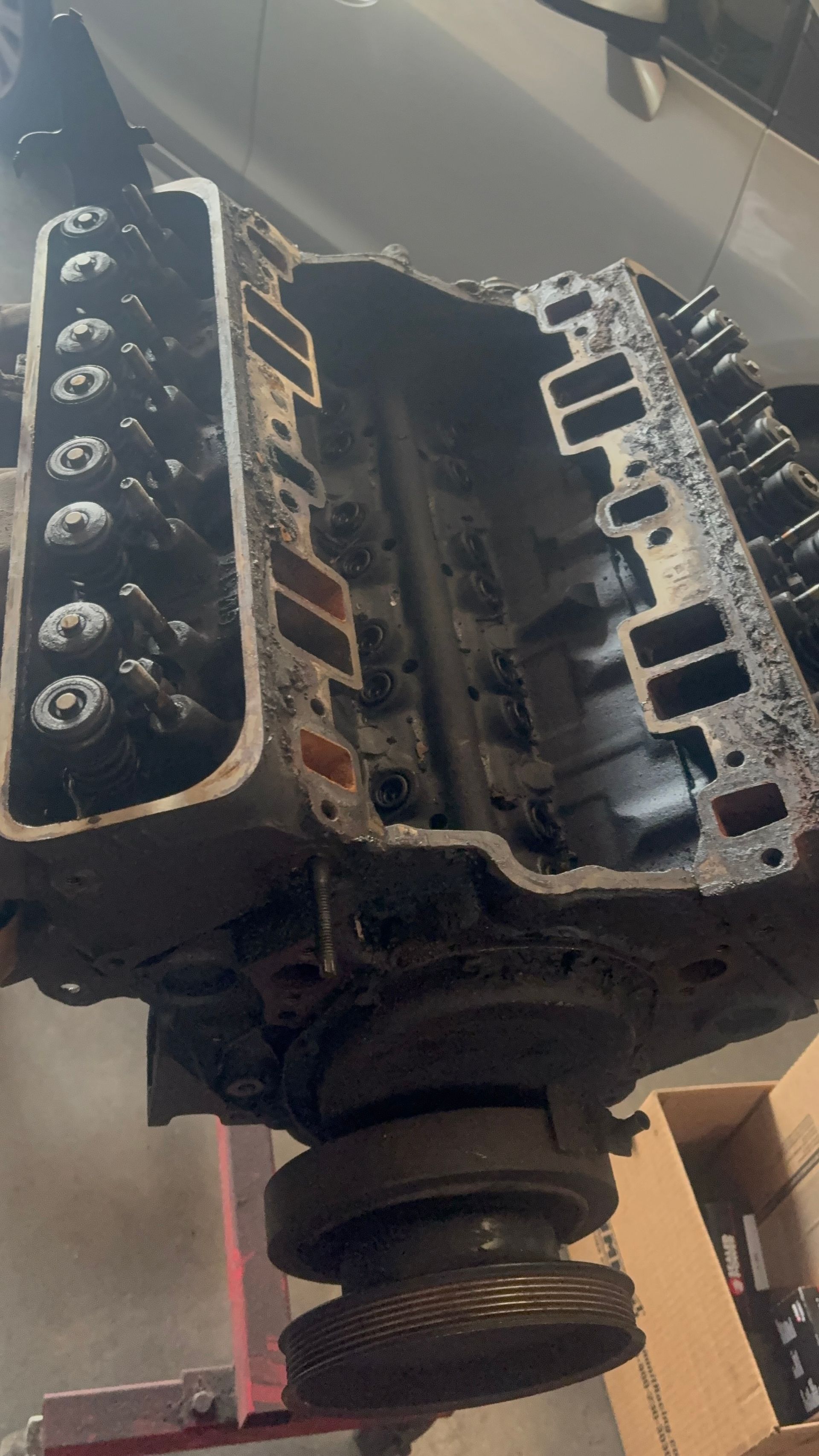Close-up of a dirty, rusted engine block with exposed cylinder heads and visible bolt holes.
