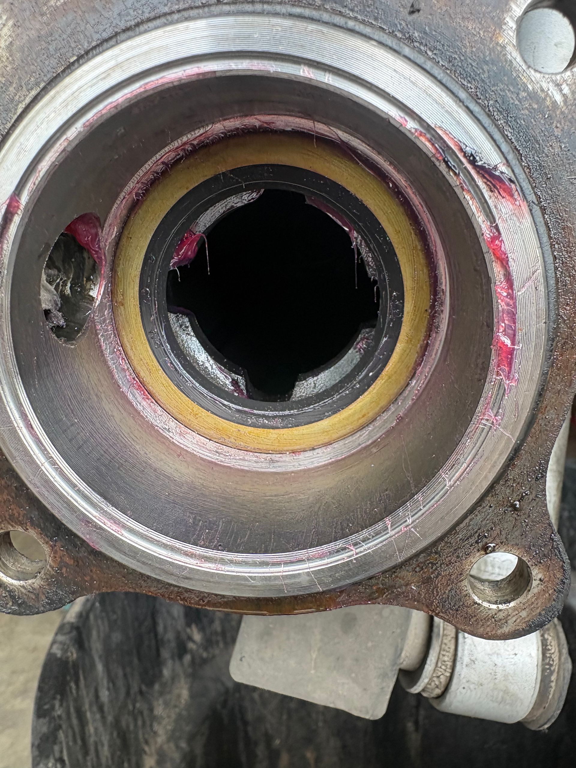 Close-up of a metal bearing housing with a central hole and pink grease residue.