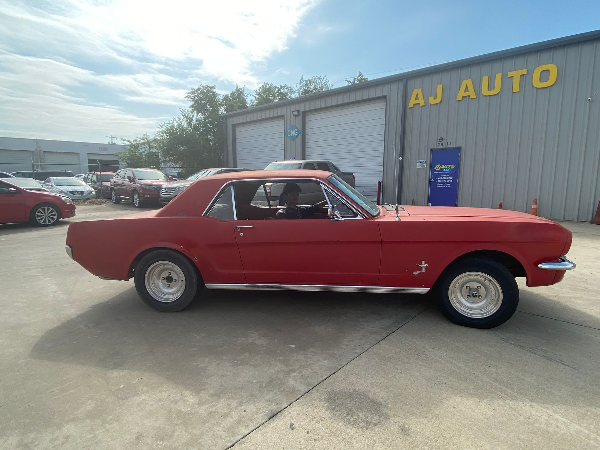 Red classic coupe parked outside AJ Auto on a sunny day