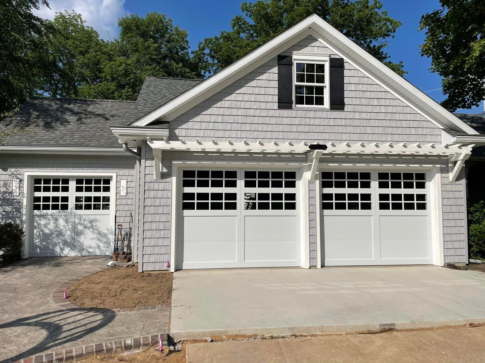 Exterior view of the top of a forest green metal building with a white roofline and garage door.