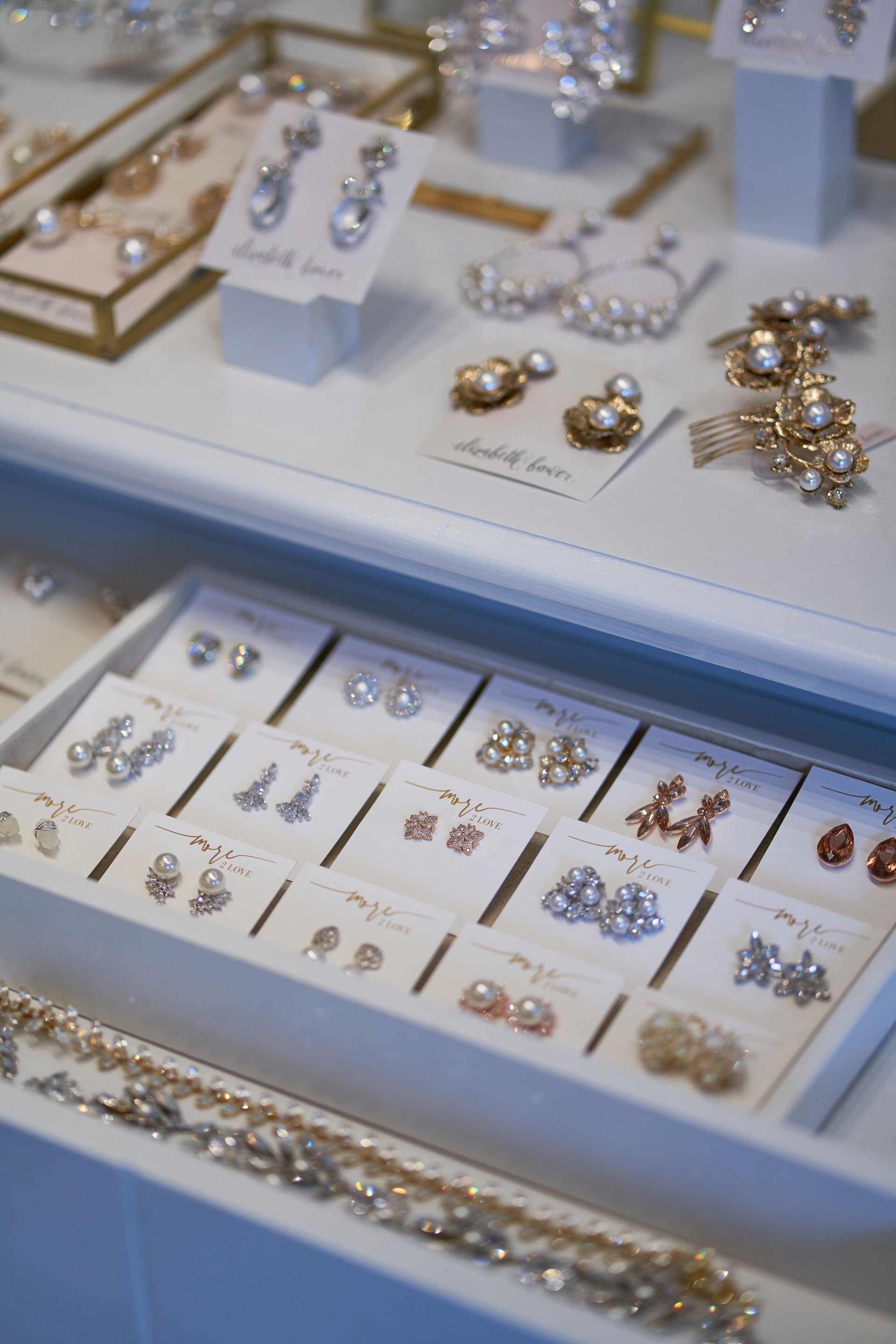 Display of pearl and crystal earrings on white trays. Close-up shot with various earring designs.