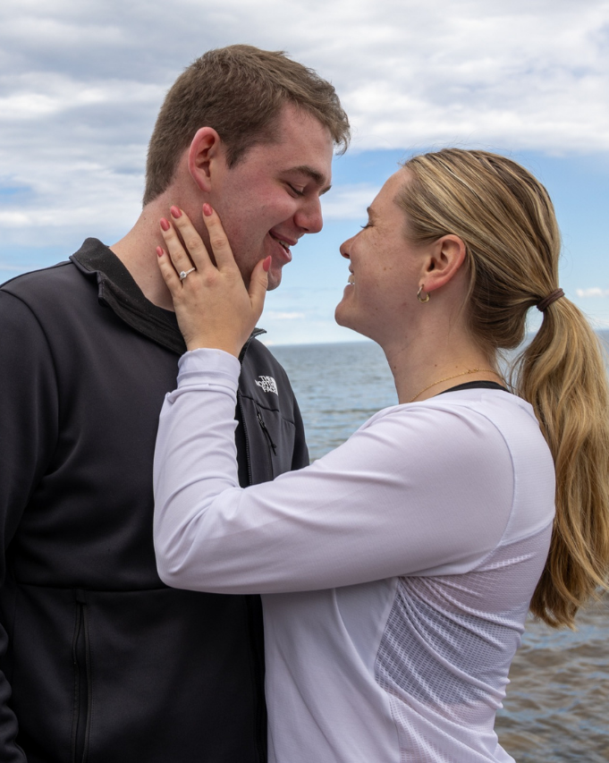 Couple smiling face to face outdoors, gently touching cheeks.