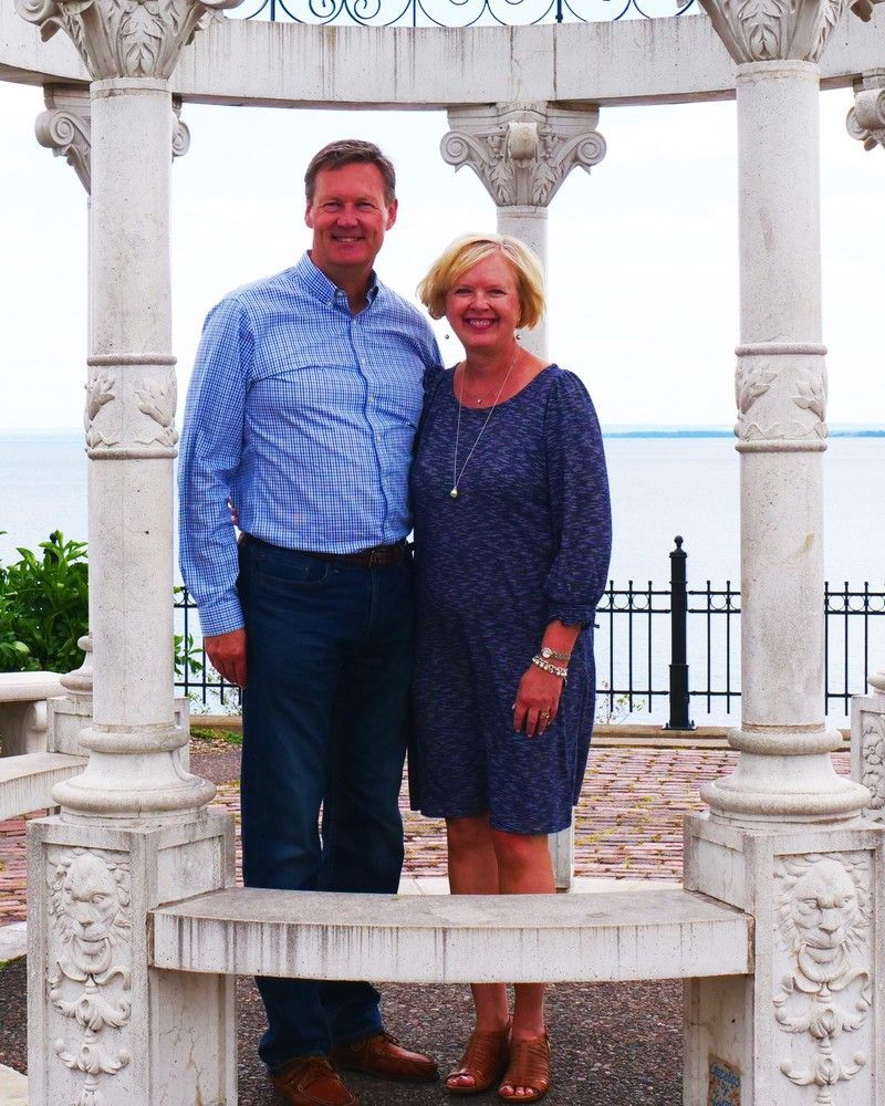 Couple smiling on a white decorative gazebo by the water