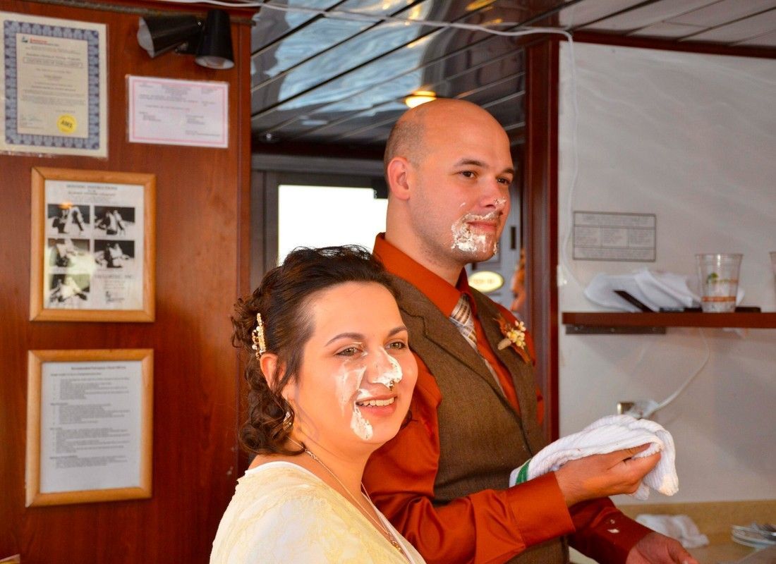 Two people with face cream smiles in a cozy indoor setting, holding a tray and plate.