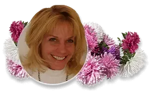 A smiling blonde person in a white top, framed within a circular border surrounded by pink and white asters.