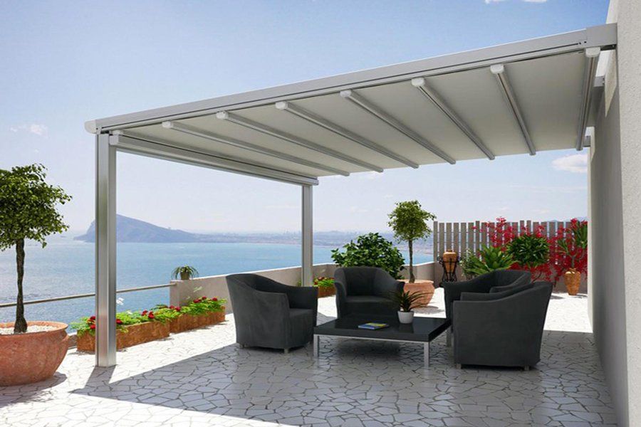 Un patio con sedie e un tavolo sotto una tettoia con vista sull'oceano.