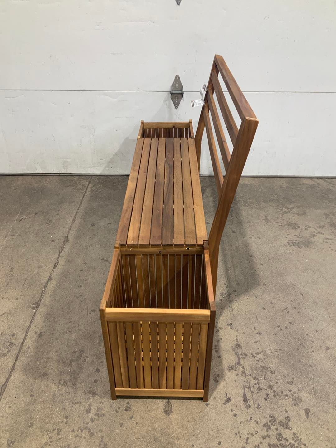 A wooden bench with a planter underneath it is sitting in front of a garage door.