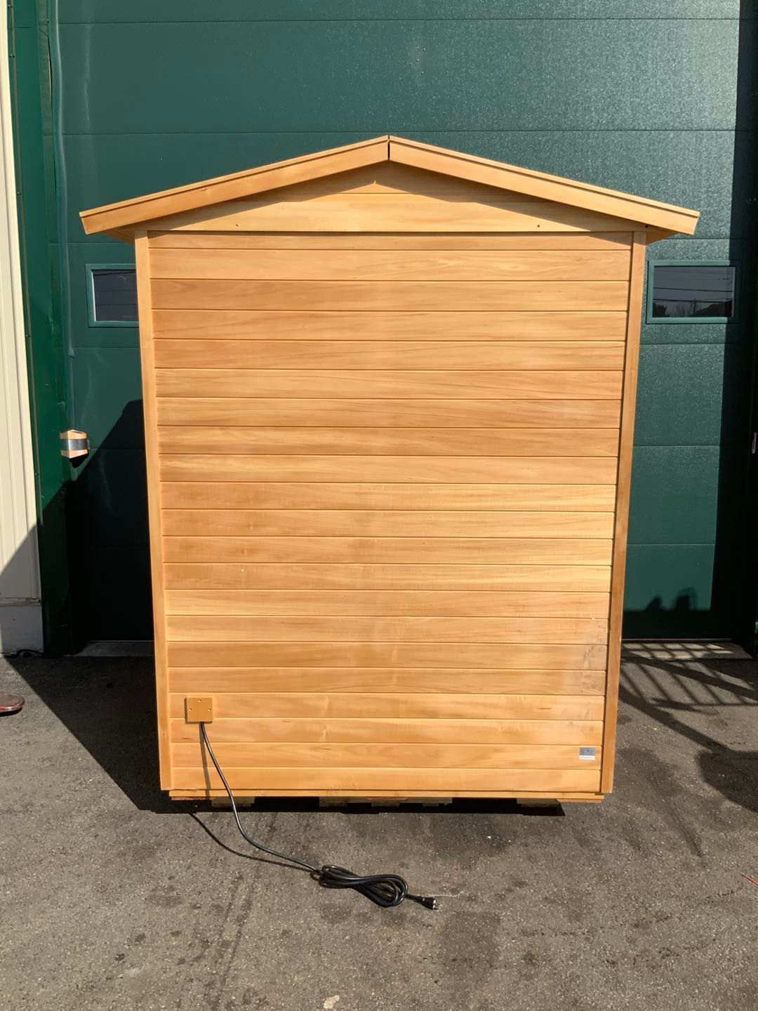 A wooden shed is sitting in front of a green garage door.