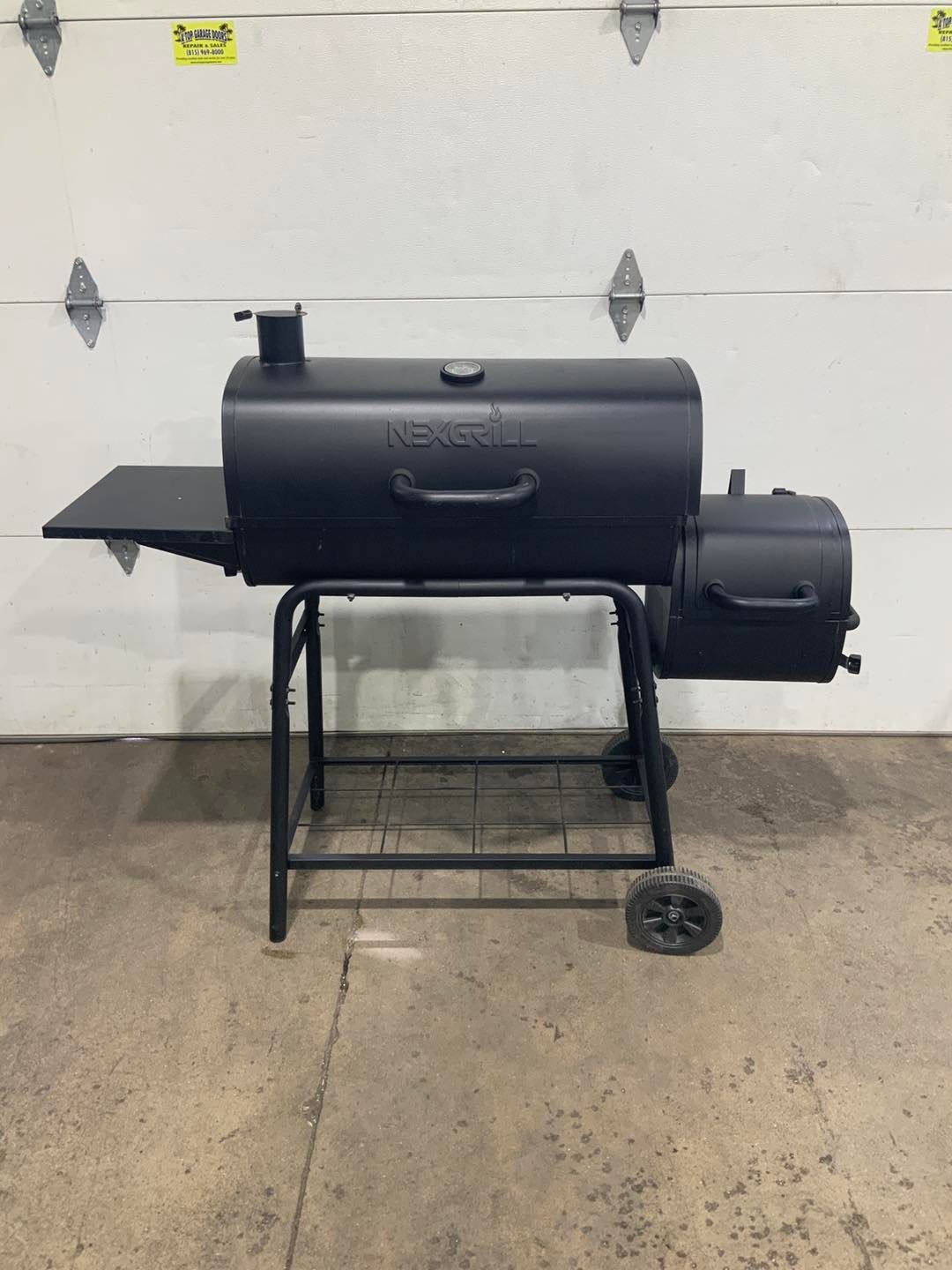 A black grill is sitting in front of a garage door.