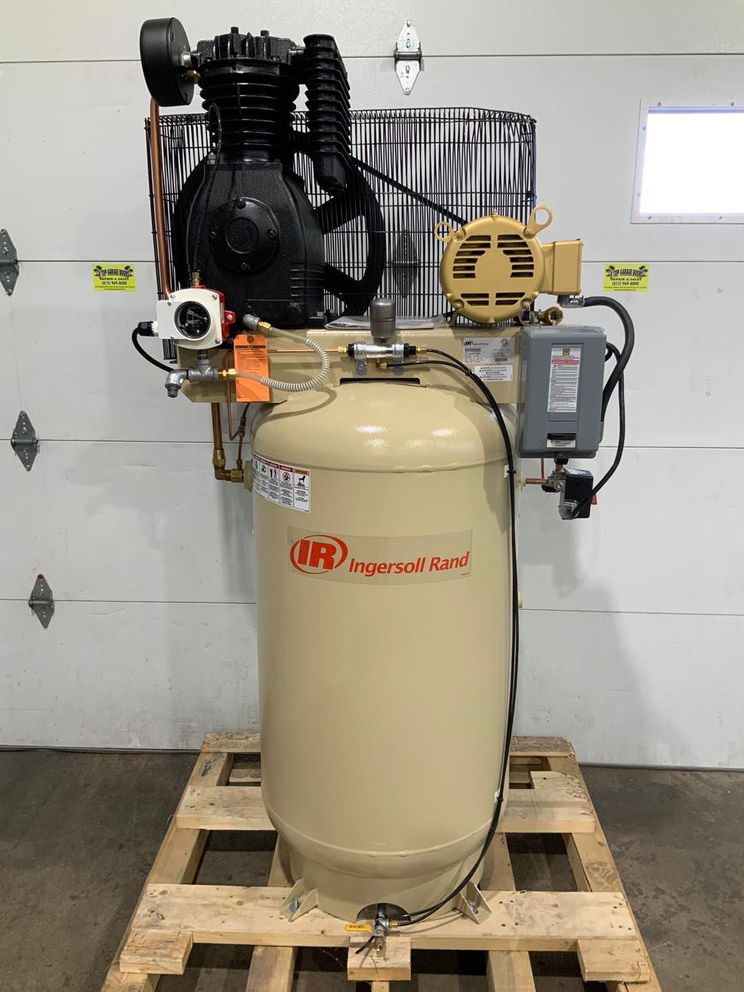 A large air compressor is sitting on top of a wooden pallet.