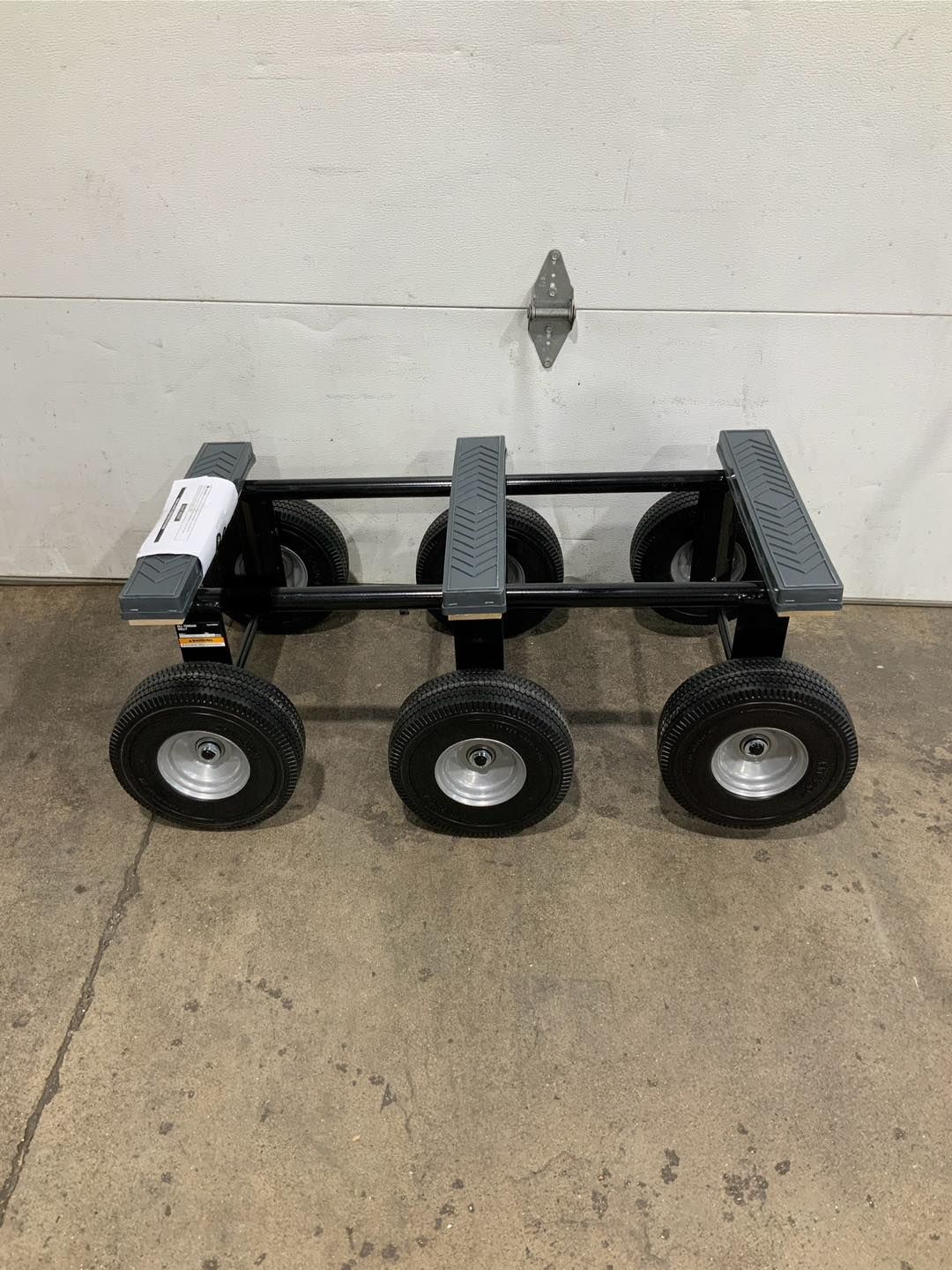 A cart with three wheels is sitting in front of a garage door.