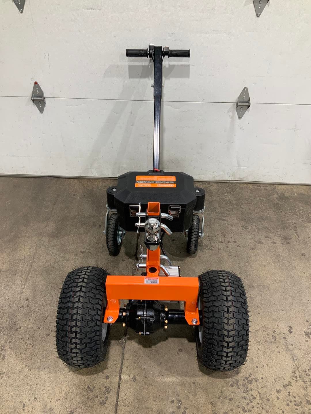 A lawn mower is parked in front of a garage door.