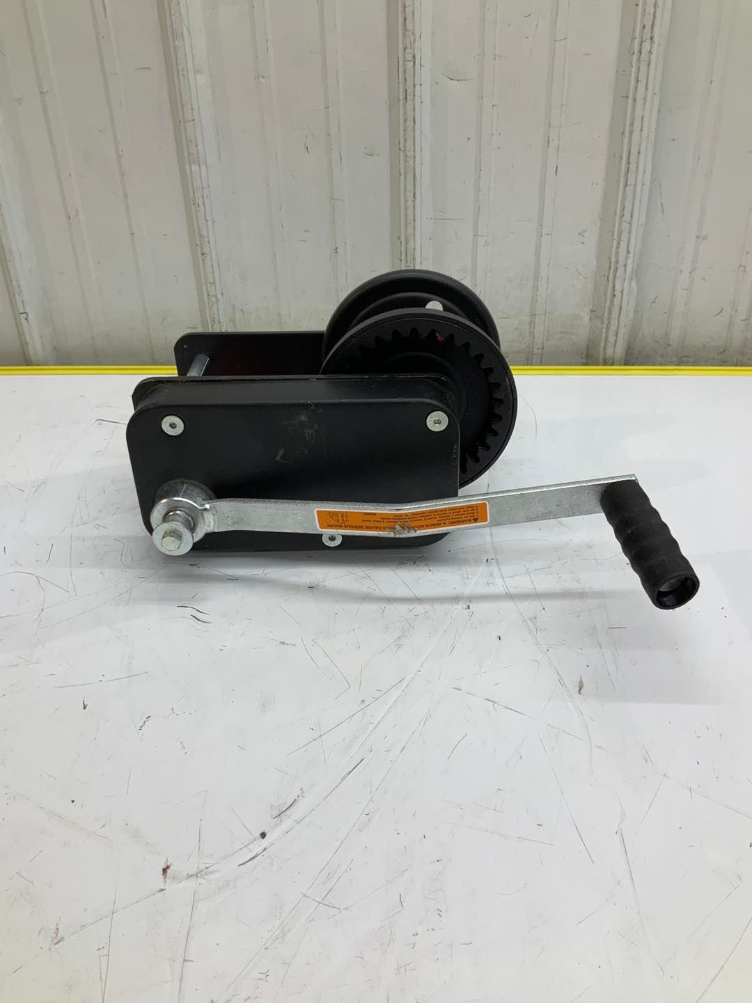 A hand winch is sitting on top of a white table.