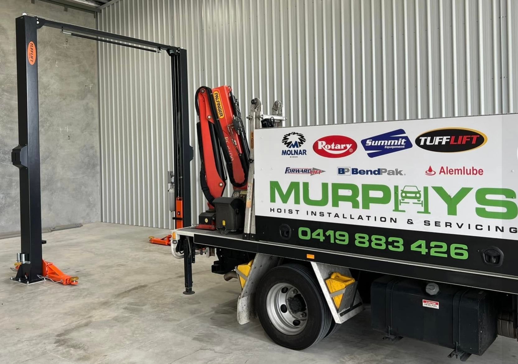 Murphy’s truck-mounted forklift parked in a warehouse, with orange safety gear and company branding visible