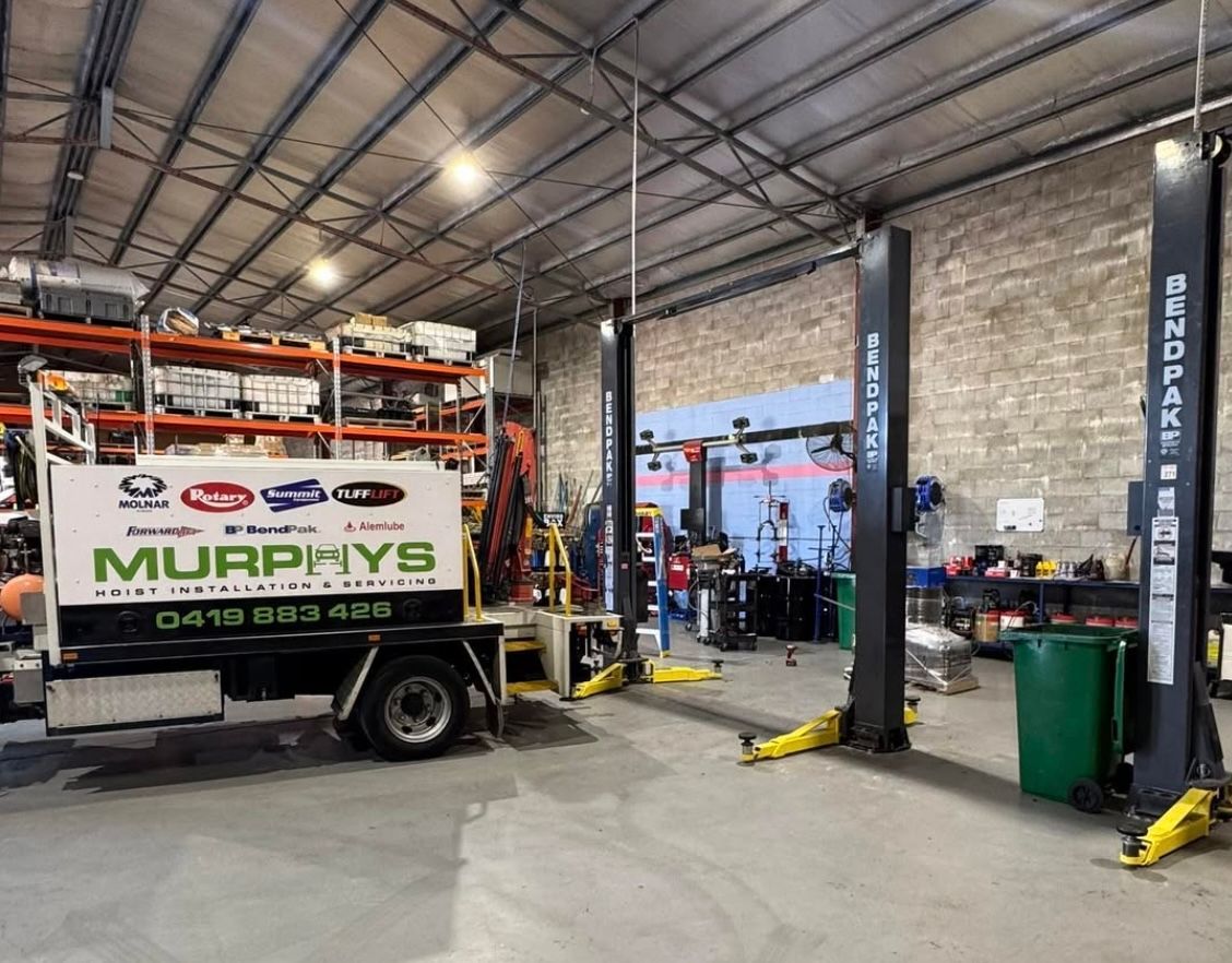 Auto repair shop with a Murphy’s service truck, vehicle lift, tools, and open garage bays