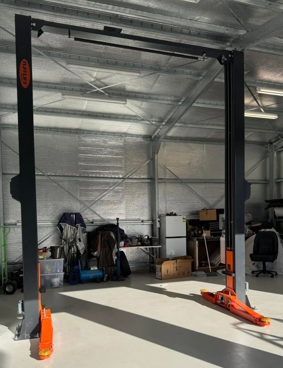 Empty garage with a car lift, tools, and storage items under a metal ceiling