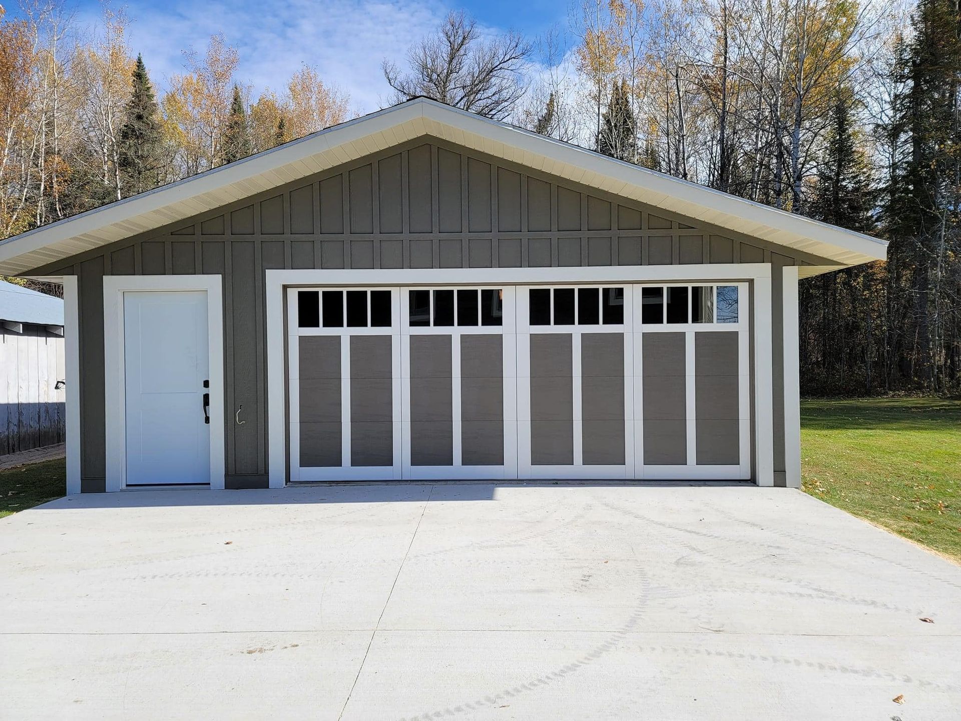 A gray garage with a white door and a concrete driveway.