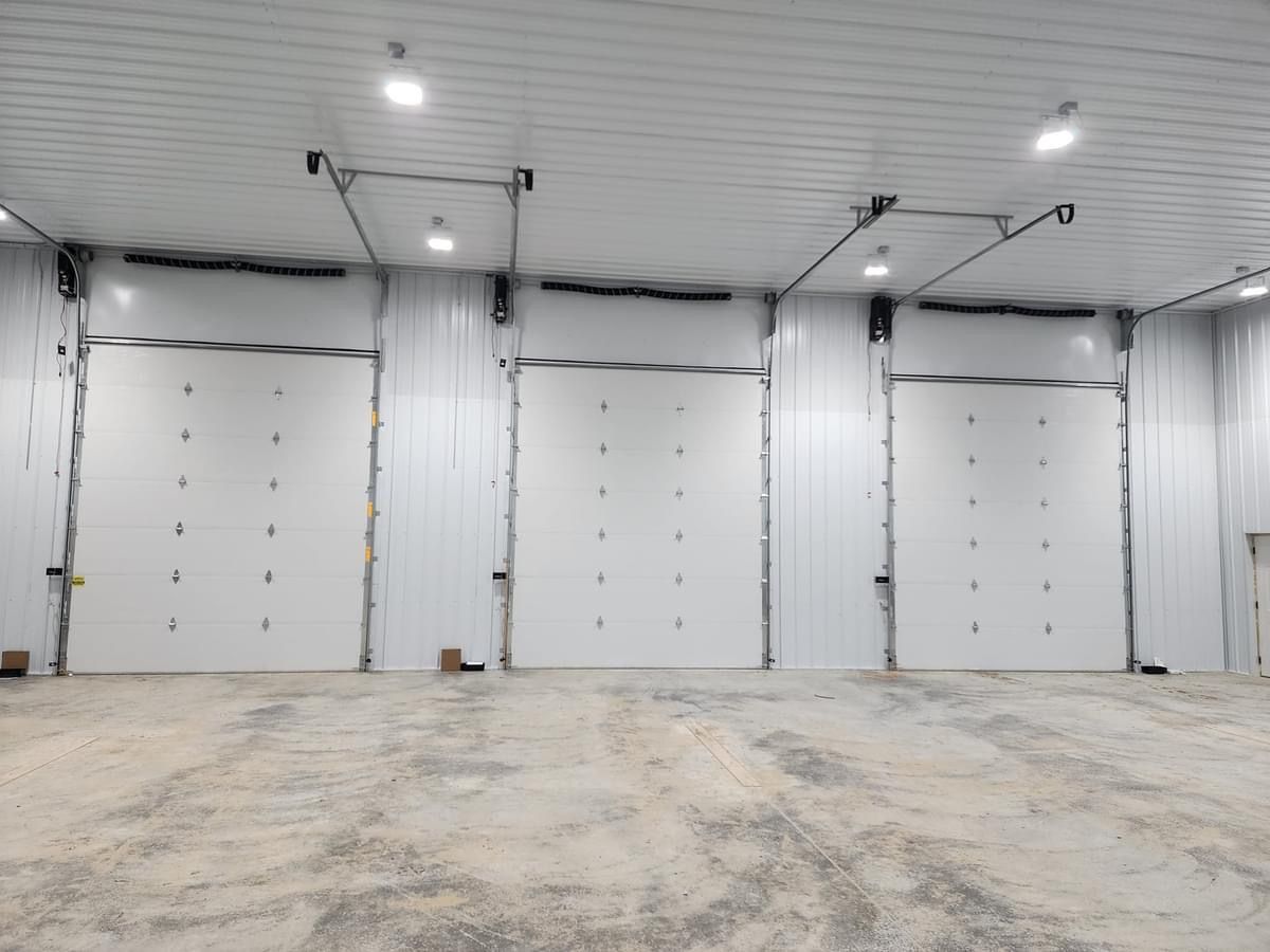 A warehouse with a lot of white doors and a concrete floor.