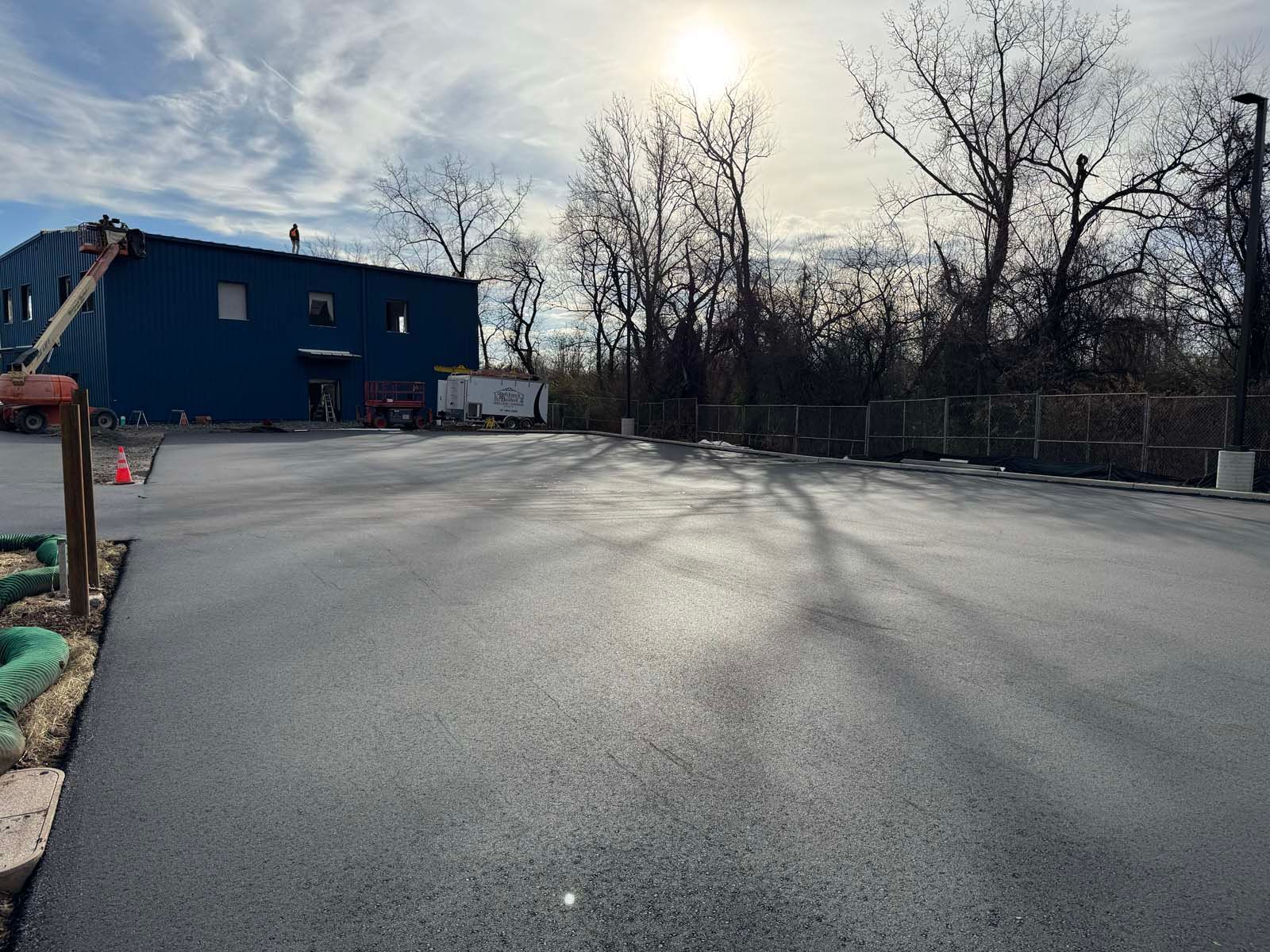 A large blue building is being built next to a parking lot.