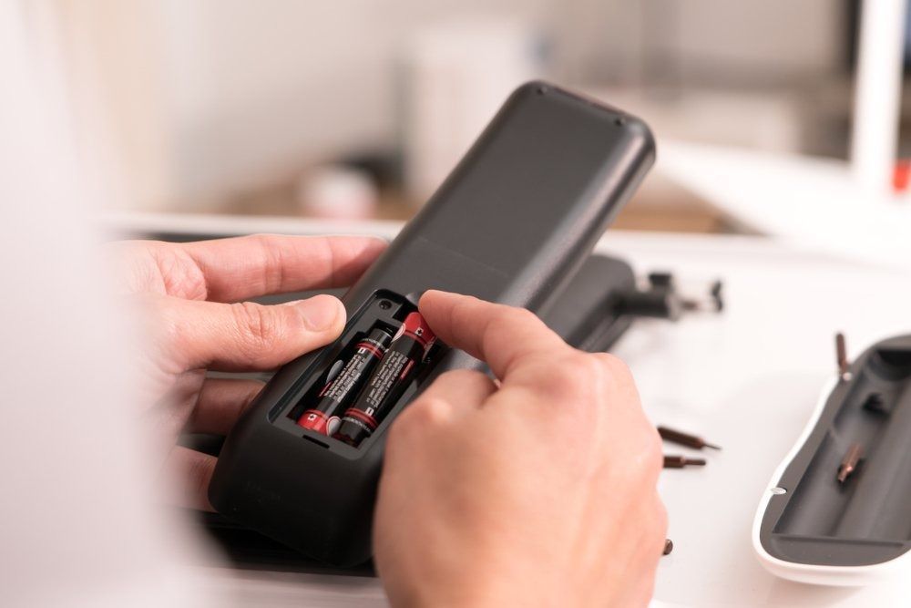 A Person is Holding a Remote Control With a Battery in It — Central Coast Batteries In Long Jetty, NSW