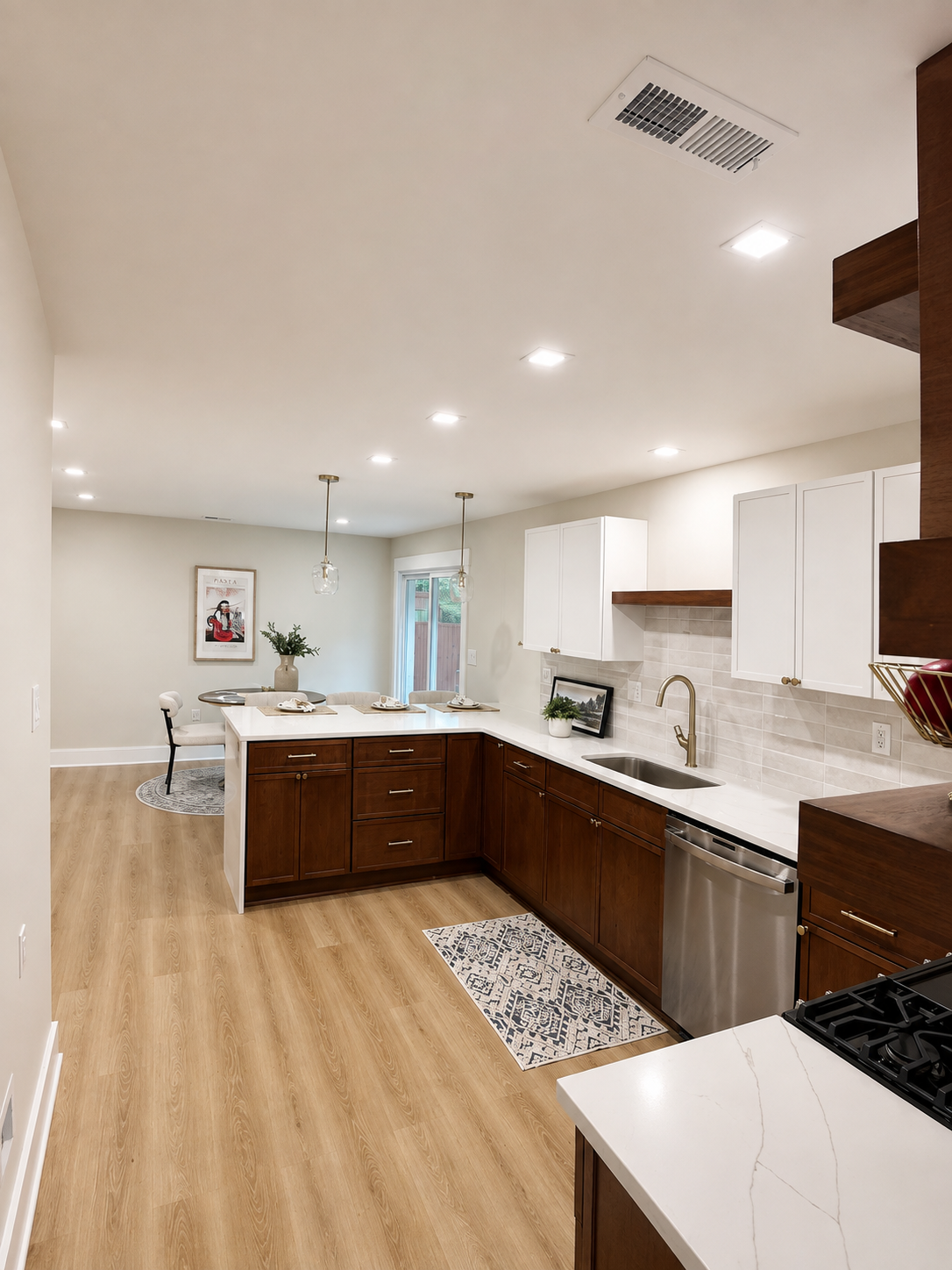 Bright modern kitchen with white cabinets, dark island, stainless appliances, and light wood floors