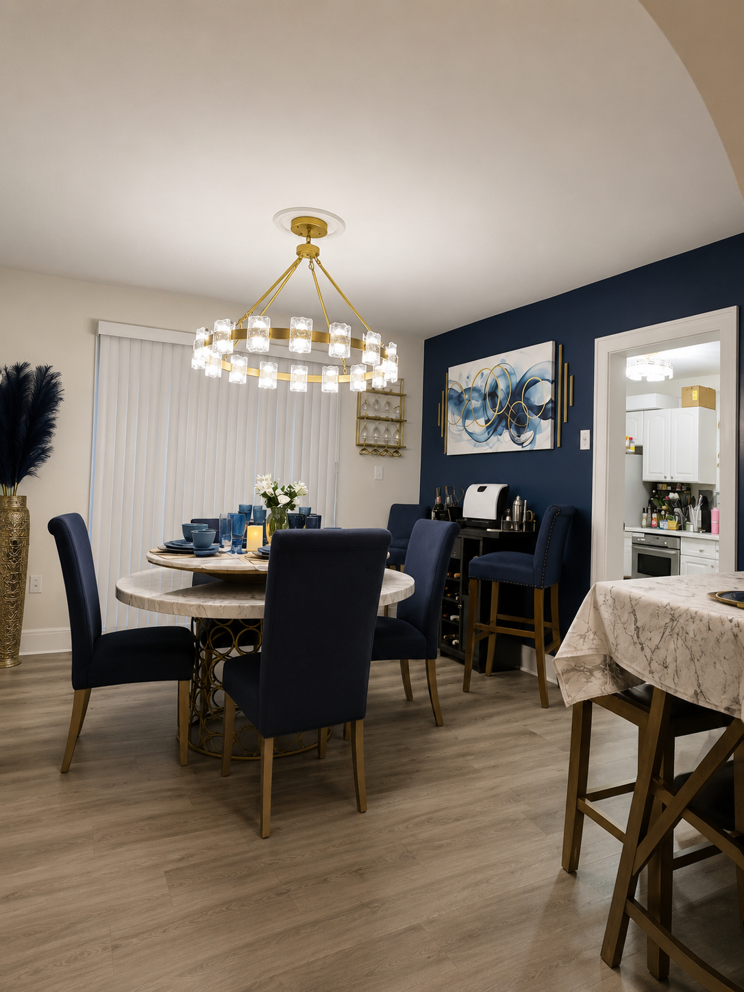 Modern dining room with a round table, navy chairs, gold chandelier, and navy accent wall
