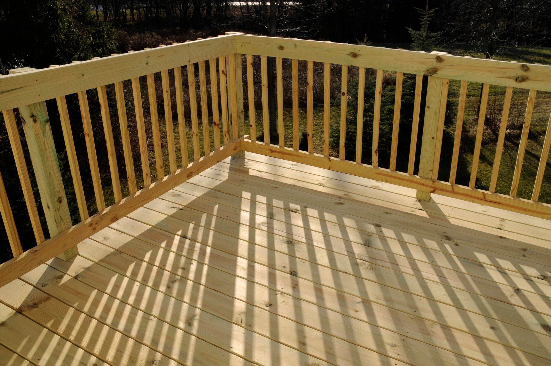 Wooden deck railing casting long shadows across a sunlit deck at sunset