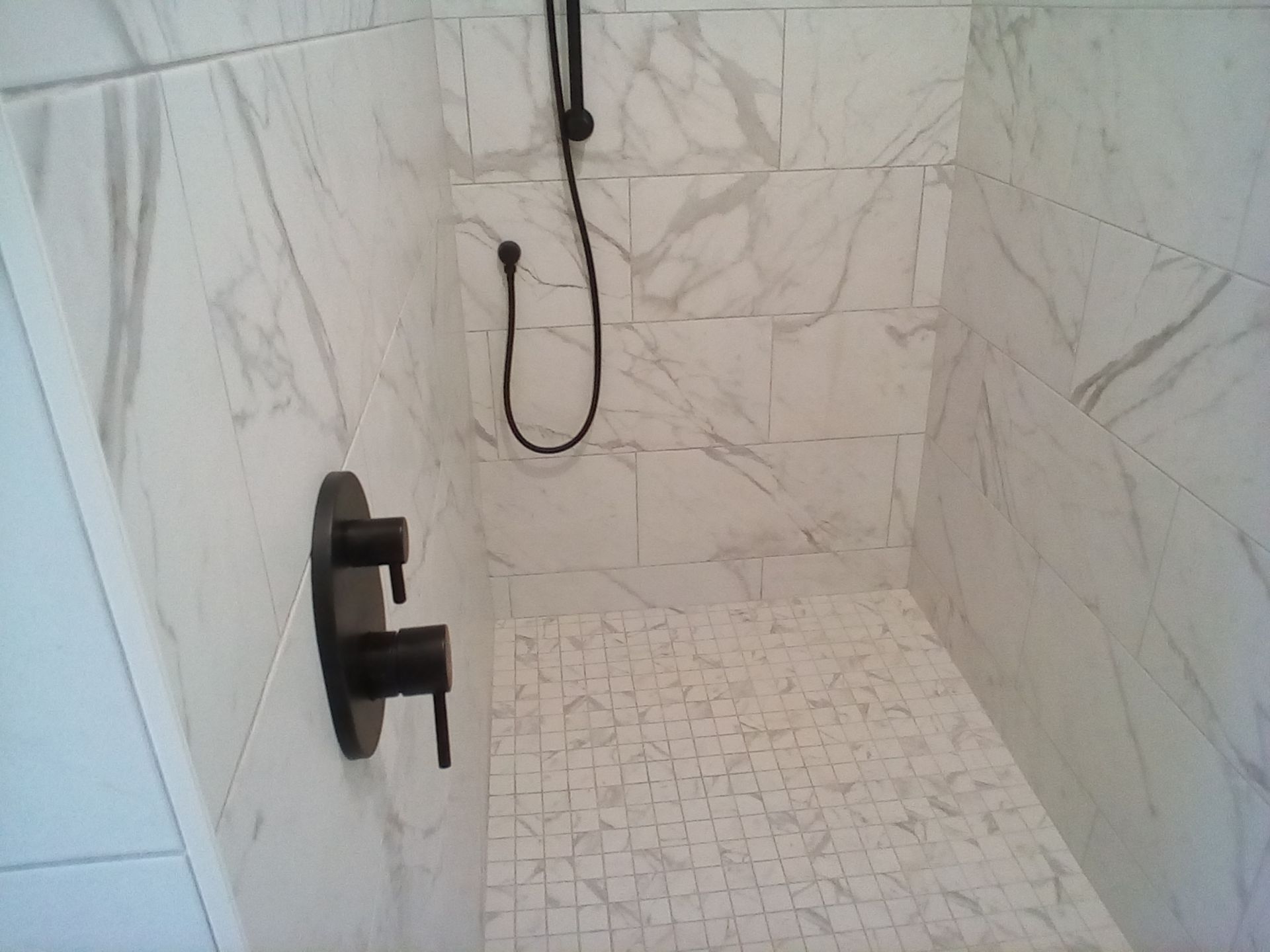 Modern tiled shower with black fixtures and a handheld showerhead