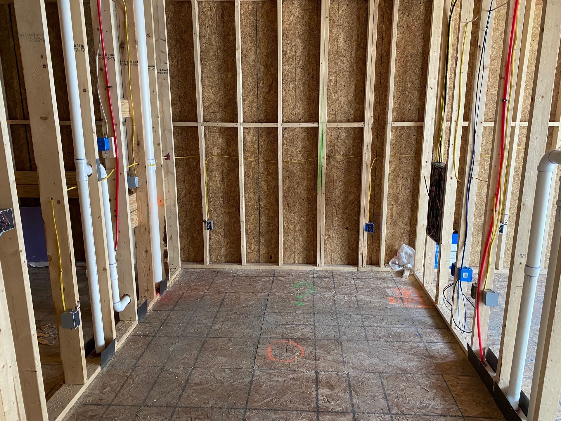Unfinished room with exposed wooden framing, insulation, and a bare subfloor under construction