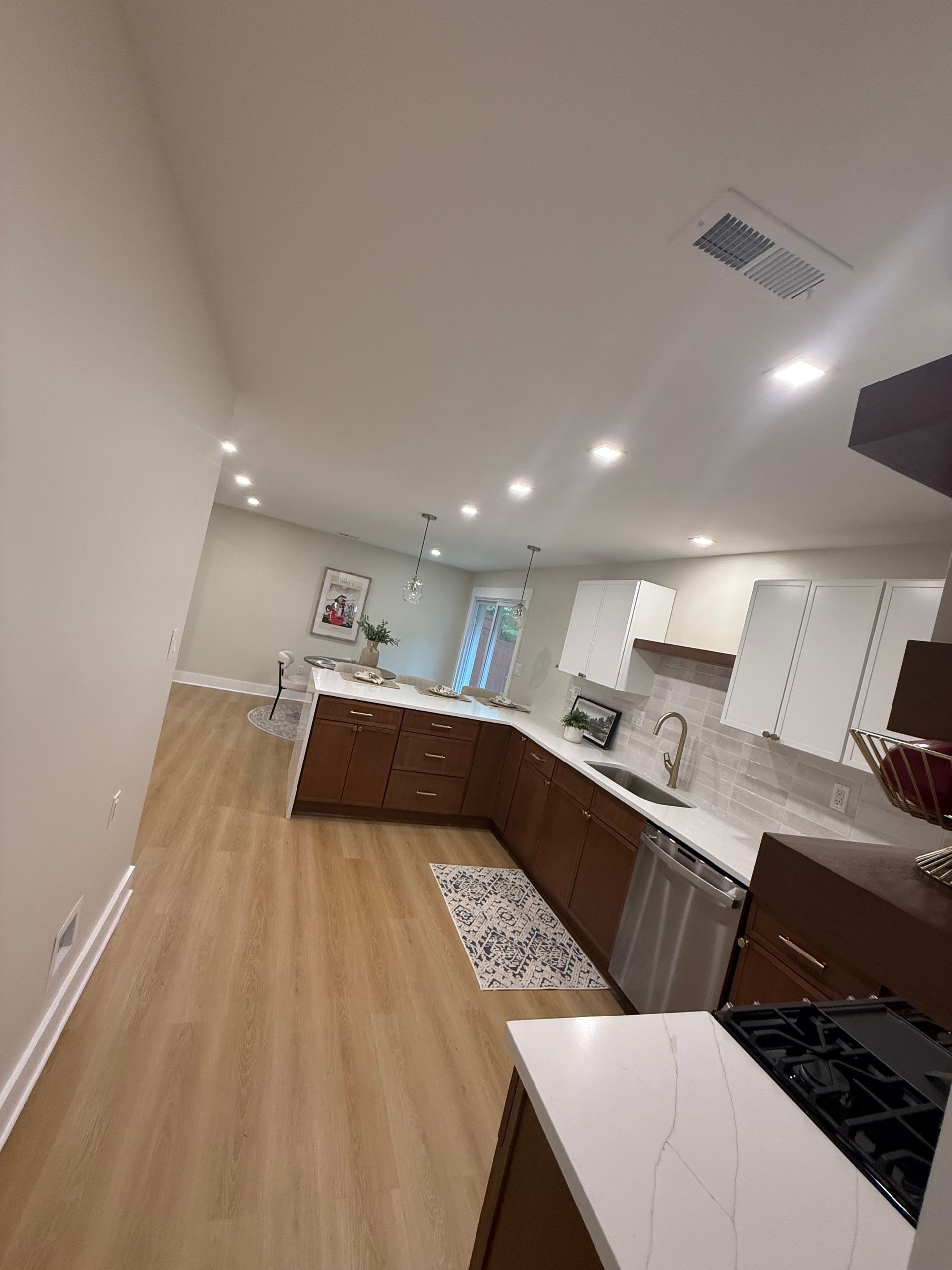 Bright modern kitchen with white cabinets, wood floors, and a large island under recessed lights