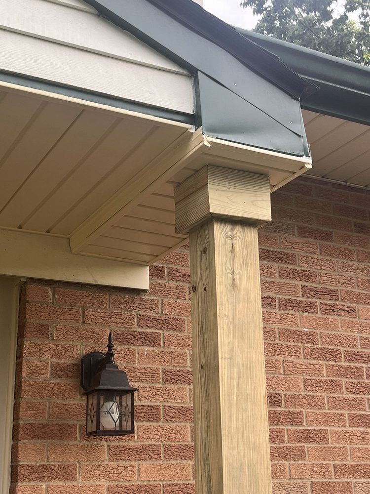 Brick house corner with damaged wooden porch support under the roof eave