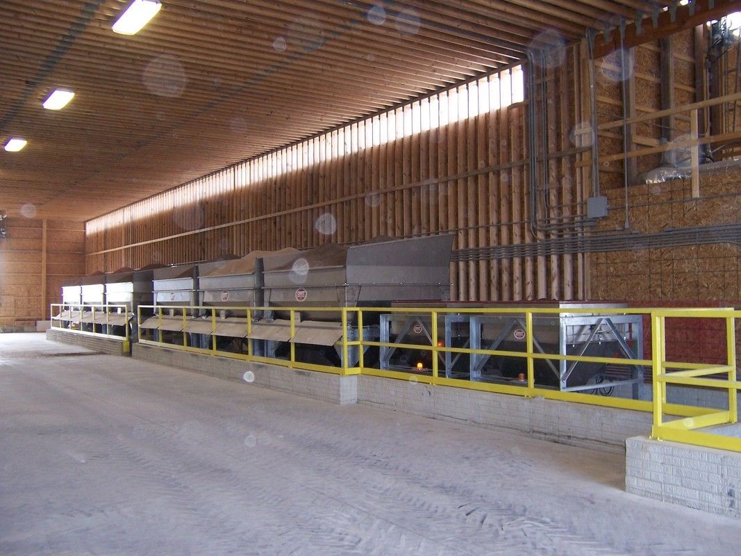 Interior of an empty industrial warehouse with yellow safety railing and machinery along the wall